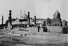 Black and white photograph of a walled city in the desert, showing domes and minarets.