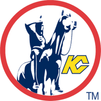 Inside a circle with a red border, a statue of a Native American scout riding a horse, and a monogram joining the letters K and C in yellow.