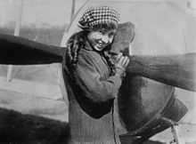 Lady standing jauntily in front of an aircraft}