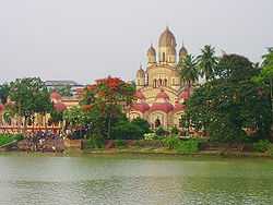 A temple with nine spires and few small temples surrounding it, with a waterbody in the foreground
