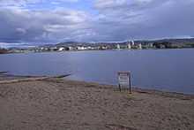A metal sign erected on the sandy shores of the lake advises of the ban on water activity due to pollution