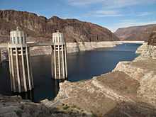 View of a reservoir where the water level has dropped, showing white deposits on the surrounding mountains