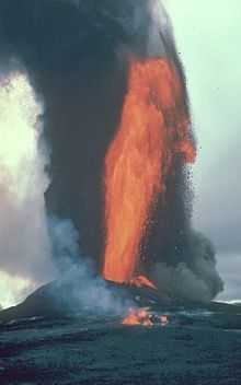 Orange fire and black smoke gushing high over the volcano.