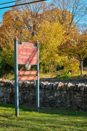 A rock wall and trees behind a large signpost