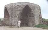 Dumbarton castle in 1800 and functioning lime kiln with smoke in the foreground.