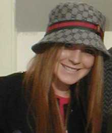 A red-haired white female wearing a black coat and a hat