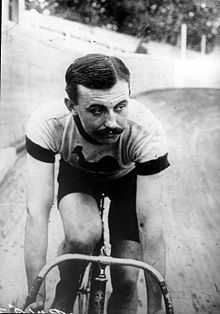 A man on a bicycle, riding on an outdoor velodrome.