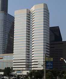  Two attached concrete and glass office towers, one with an irregular shape. Both have uniform horizontal bands of windows alternating with the concrete.