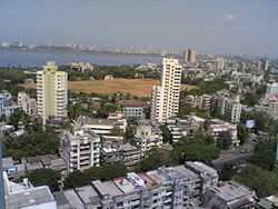 high rise buildings surround a park, with the ocean beyond