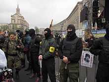 A line of five Patriot of Ukraine members (some with bats) providing security at a meeting organized by Right Sector activists, at the Euromaidan’s main stage
