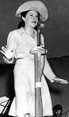 Woman singing behind a microphone stand and big hat