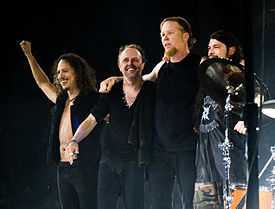 Members of Metallica embracing and smiling onstage