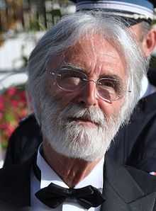 Headshot of a bearded, grey-haired man with glasses. He is wearing a tuxedo and a black bowtie.