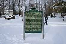 State of Michigan Historical marker with gold text on a green background, standing in a field of snow