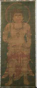 Frontal portrait of a frightening deity dressed only in a skirt-like garment holding a sword in his right hand.