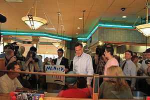 Photograph of Romney working a lunch counter line, with citizens and press photographers crowding around