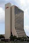 Ground-level view of a 20-story building with a tan stucco facade.