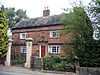 A sandstone house behind a pair of ornamental gateposts (which are listed separately)