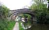 The bridge crosses the canal with a wide footpath on the left and long boats visible through the arch.