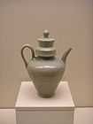 A green tinted grey teapot with a small base and a tall body in the shape of an cone with the smallest point facing downwards. The cap covering the point that the water is poured into is a tall cylinder, and fits into a thick, wide cylindrical rim in the pot.