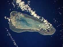 A satellite view of a bare, triangle-shaped island surrounded completely by water.