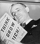 head shot of a man with head tilted and rested on the back of his right hand while reading a book