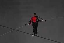 A man in black and red on a tightrope