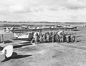 Men in flying suits with single-engined several military biplanes