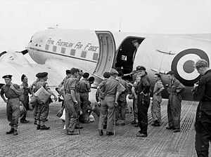 Uniformed personnel boarding a twin-engined transport plane