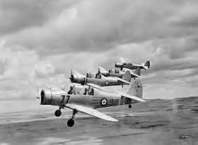 Three-quarter view of four military monoplanes in flight