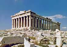 The Parthenon is a rectangular building of white marble with eight columns supporting a pediment at the front, and a long line of columns visible at the side