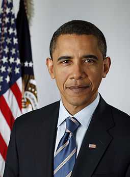 First official presidential portrait of Barack Obama, wearing a black suit with a blue tie and American flag lapel pin, indoors with the American flag and the flag of the President draped in the background