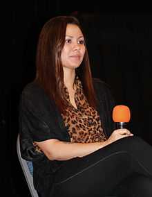 A woman with black hair is seated at a table.