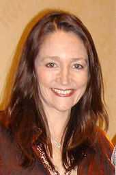 Head and shoulders of an older woman with long brown hair smiling