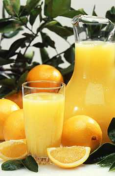 A jar of orange juice with oranges around it