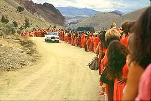 White car passing saffron-robed people on mountain road