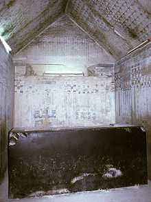 Small stone chamber, its walls inscribed with hieroglyphs and its gabled roof covered with painted stars. At the center is a massive but broken black sarcophagus.