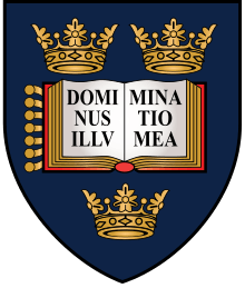A shield displaying a coat of arms; on a dark blue background, an open book displays the words "Dominus Illuminatio Mea"; two gold crowns above, one below