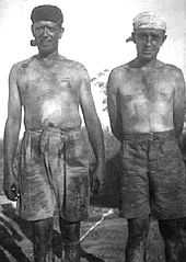 Two men stripped to waist and covered in coal dust, one smoking a pipe