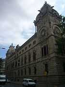 Large old stone building, with vehicles nearby for scale