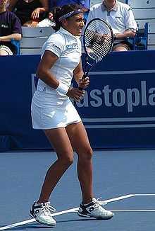 A lady facing forward holding a tennis racket out in front of her body