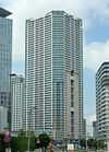 Ground-level view of a white, orange and green rectangular high-rise; its balconies form horizontal stripes up the height of the tower