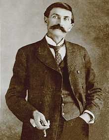 black and white photo of slender man in old-fashioned suit and sporting a large moustache