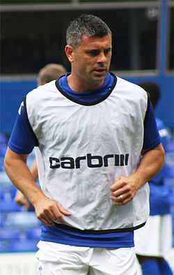 Grey-haired man wearing blue and white sports clothing