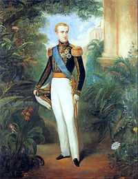 Full-length painted portrait of a blond young man standing in a garden dressed in white trousers, a military tunic with heavy gold braid, a blue sash of office, and holding a bicorn admiral's hat