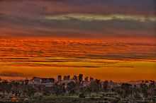 a photo of the reds and oranges of a sunset over the skyline of Phoenix, as seen from Papago park.