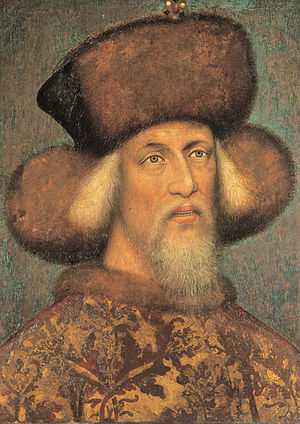 An elderly bearded man wearing a hat made of fur