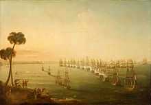 A broad view of a bay. Running vertically from the foreground to the background is a line of 14 anchored ships flying red, white and blue tricolour flags. to their left are four more anchored ships and to the left of these vessels is a distant shoreline. In the foreground of this shore is a hillside on which several men in turbans watch the scene below. To the right of the line a number of ships with all sails set are grouped around the head of the line, as smoke rises from many of the ships on both sides.