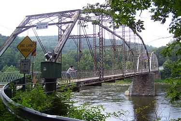 A view along a bridge with metal girders overhead and a wooden deck