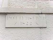 A white wall carries a stone plaque engraved with the word "Pottersfield" in upper case letters. Below this are the numerals "1822".